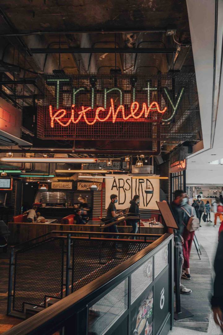 Neon Sign For Leeds Trinity Kitchen With People Walking Past
